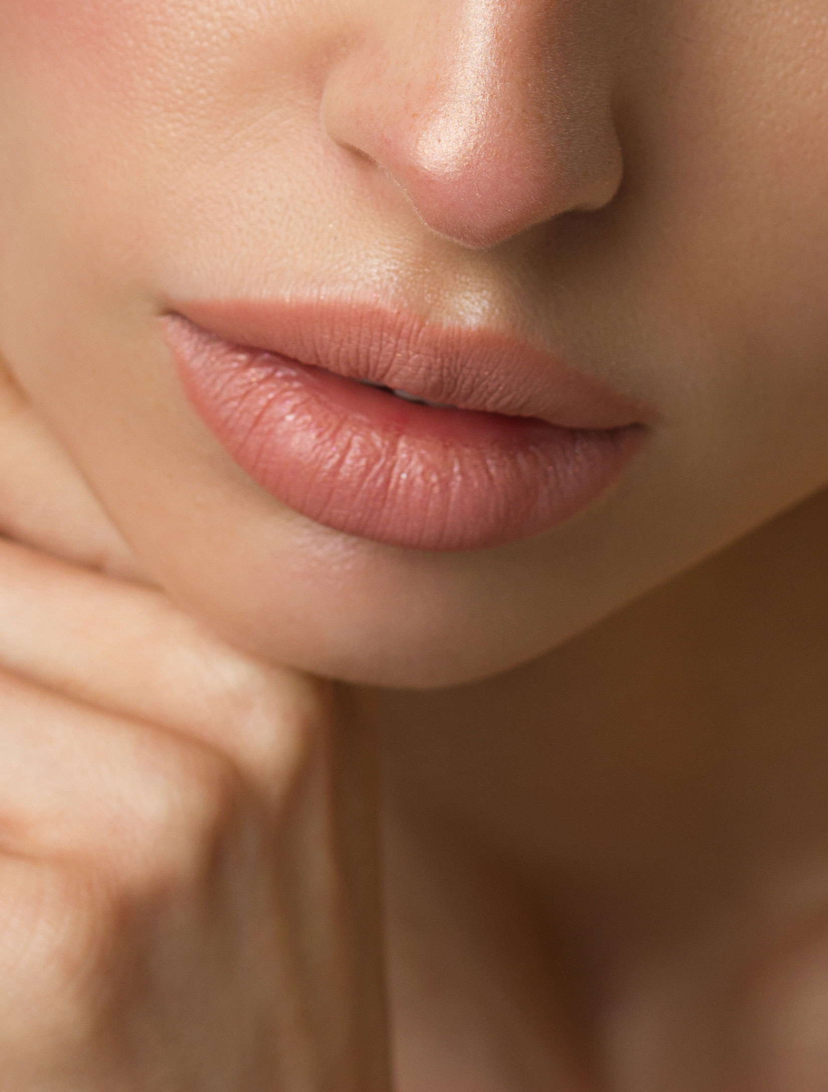 Close-up of a person's lips and nose, with soft lighting highlighting the smooth texture of the skin and the natural contours of the face
