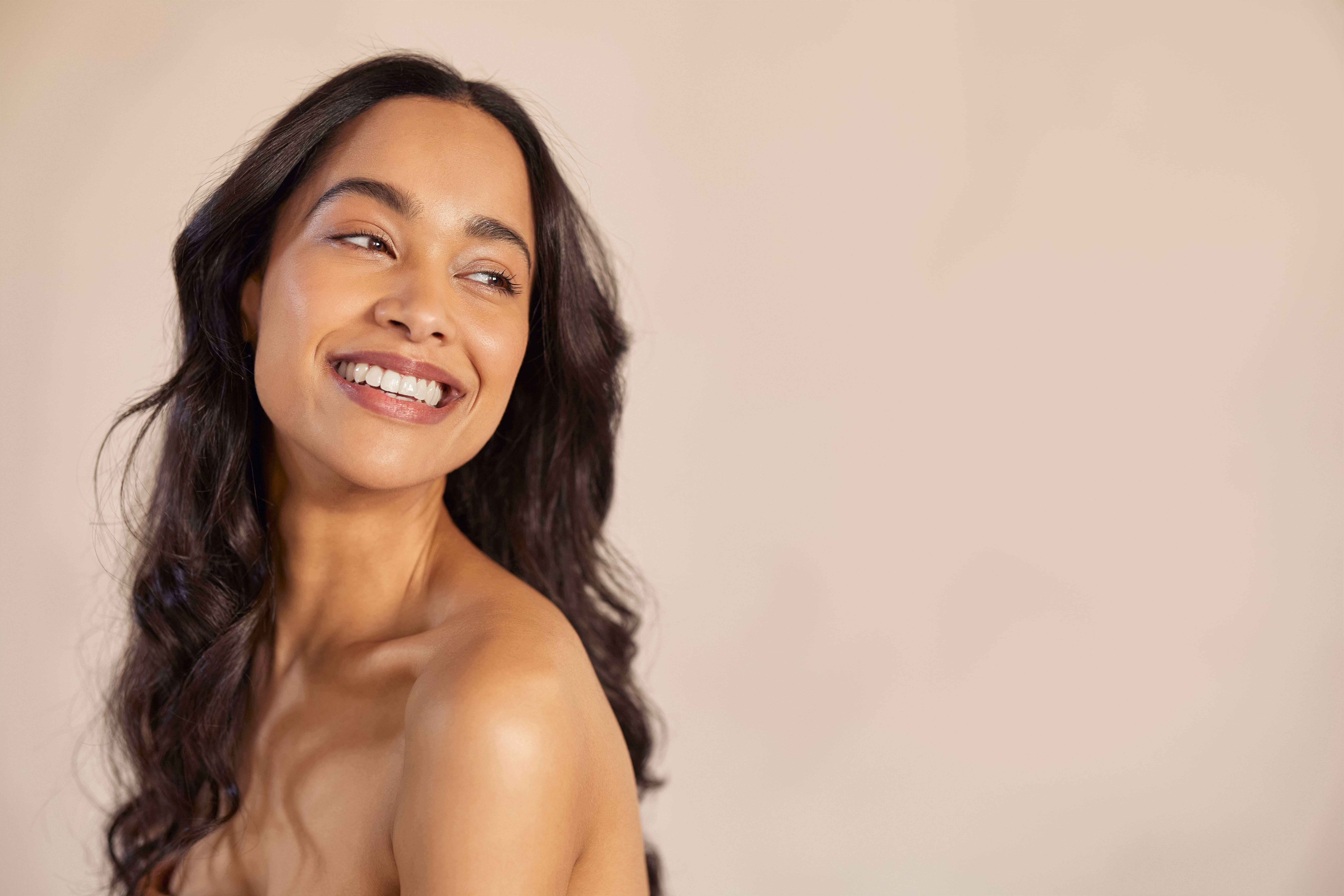 Confident woman with radiant skin and long dark hair, representing natural beauty and wellness