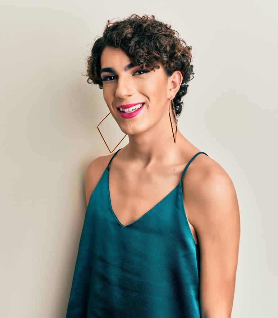 Photo of a smiling trans woman wearing big earrings and a green top