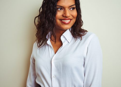 Photo of a happy trans woman wearing a white blouse after chest feminization surgery