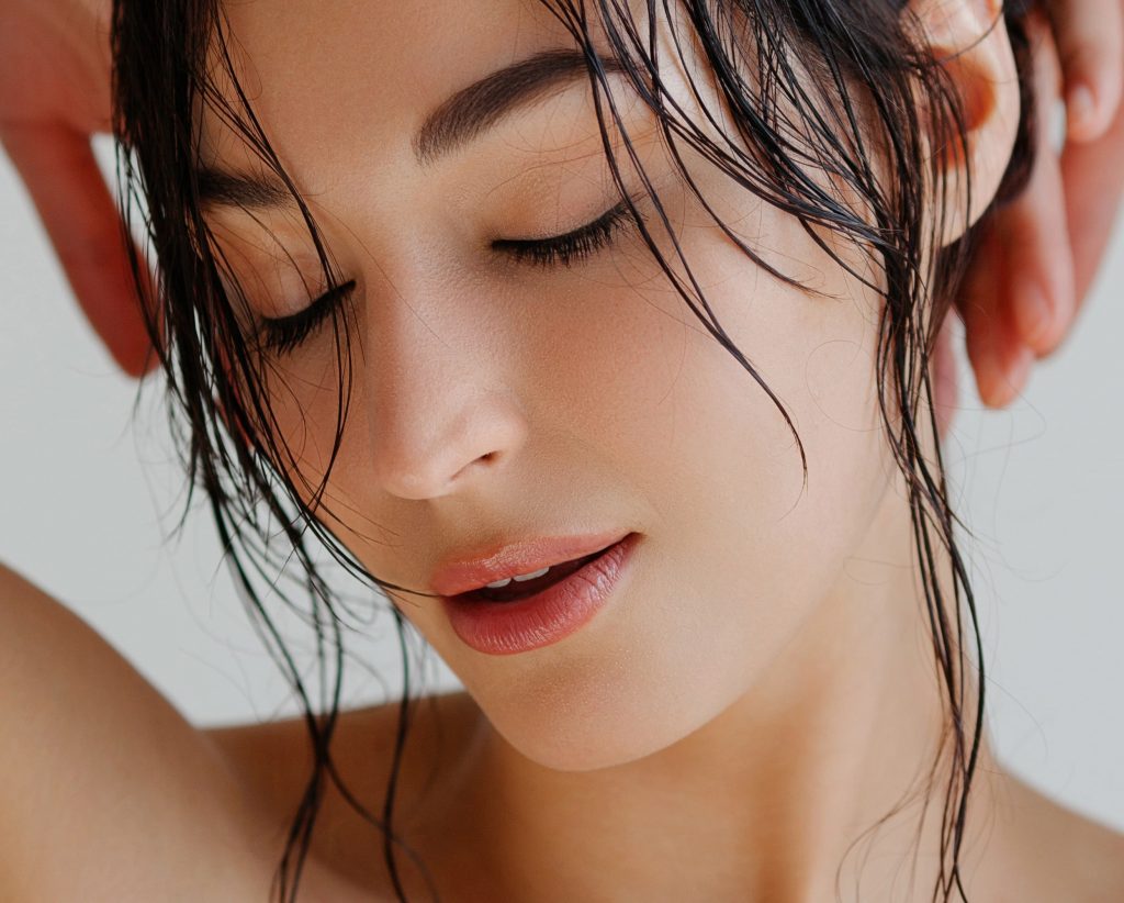 Photo of a woman with wet hair and great skin closing her eyes