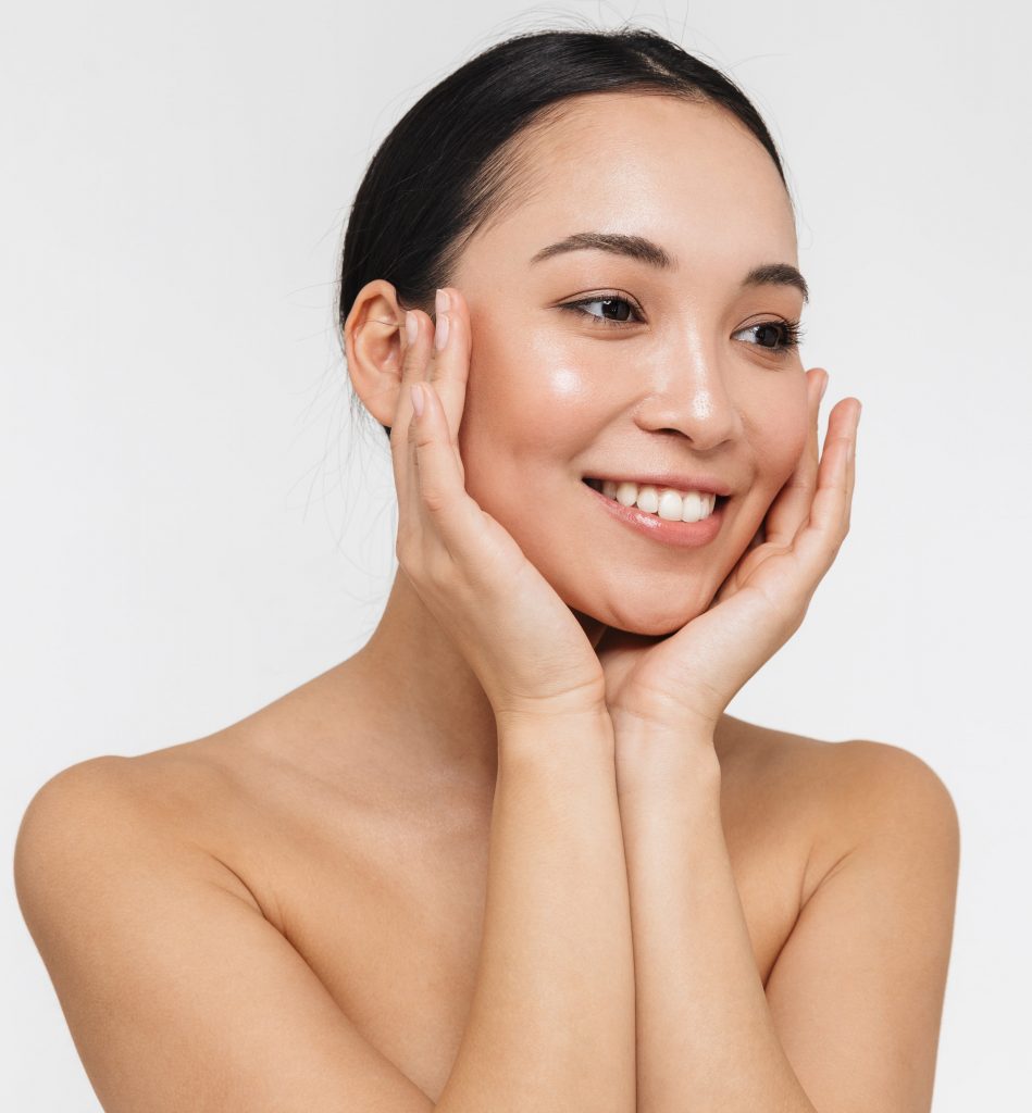 Photo of a smiling woman with amazing skin touching the sides of her cheeks