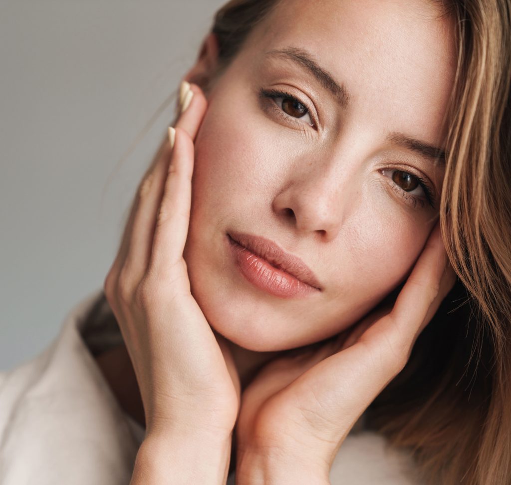 Photo of a woman with blonde hair and brown eyes resting her head in her hands