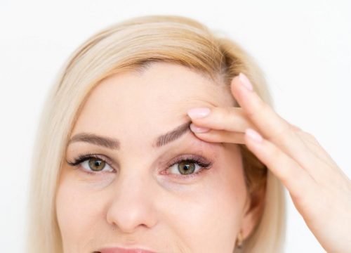Photo of a woman lifting her left eyebrow with her fingers
